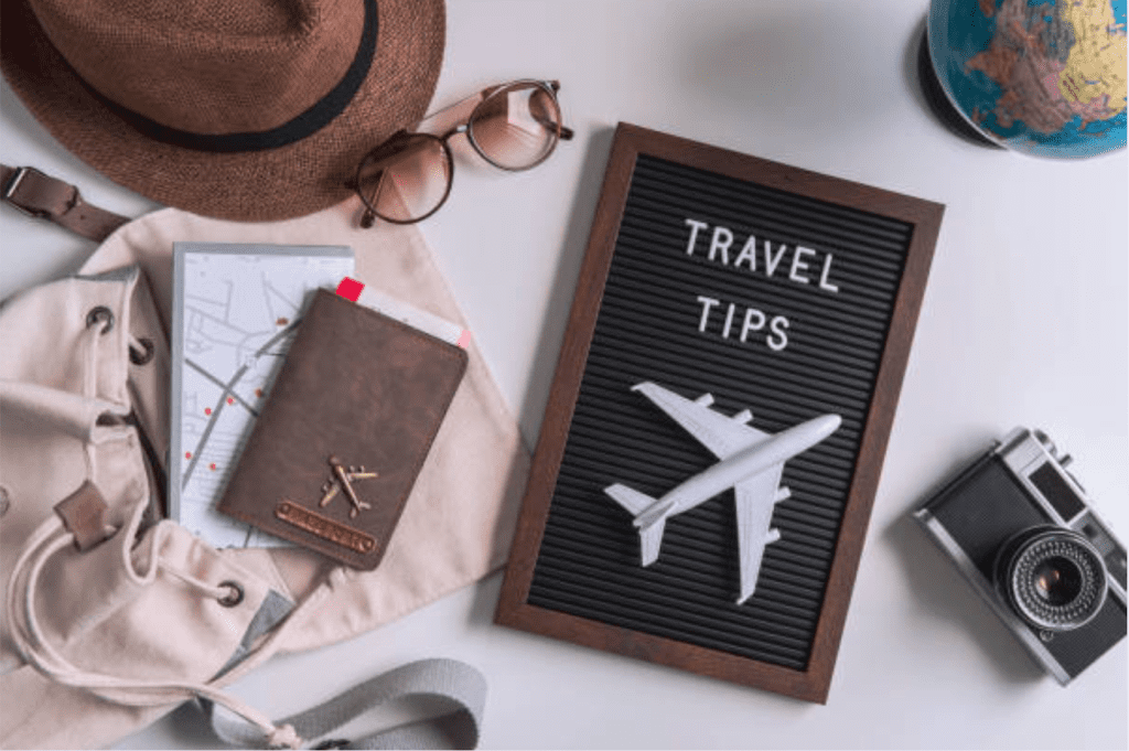 Flat lay of travel essentials including passport, plane model and travel guide